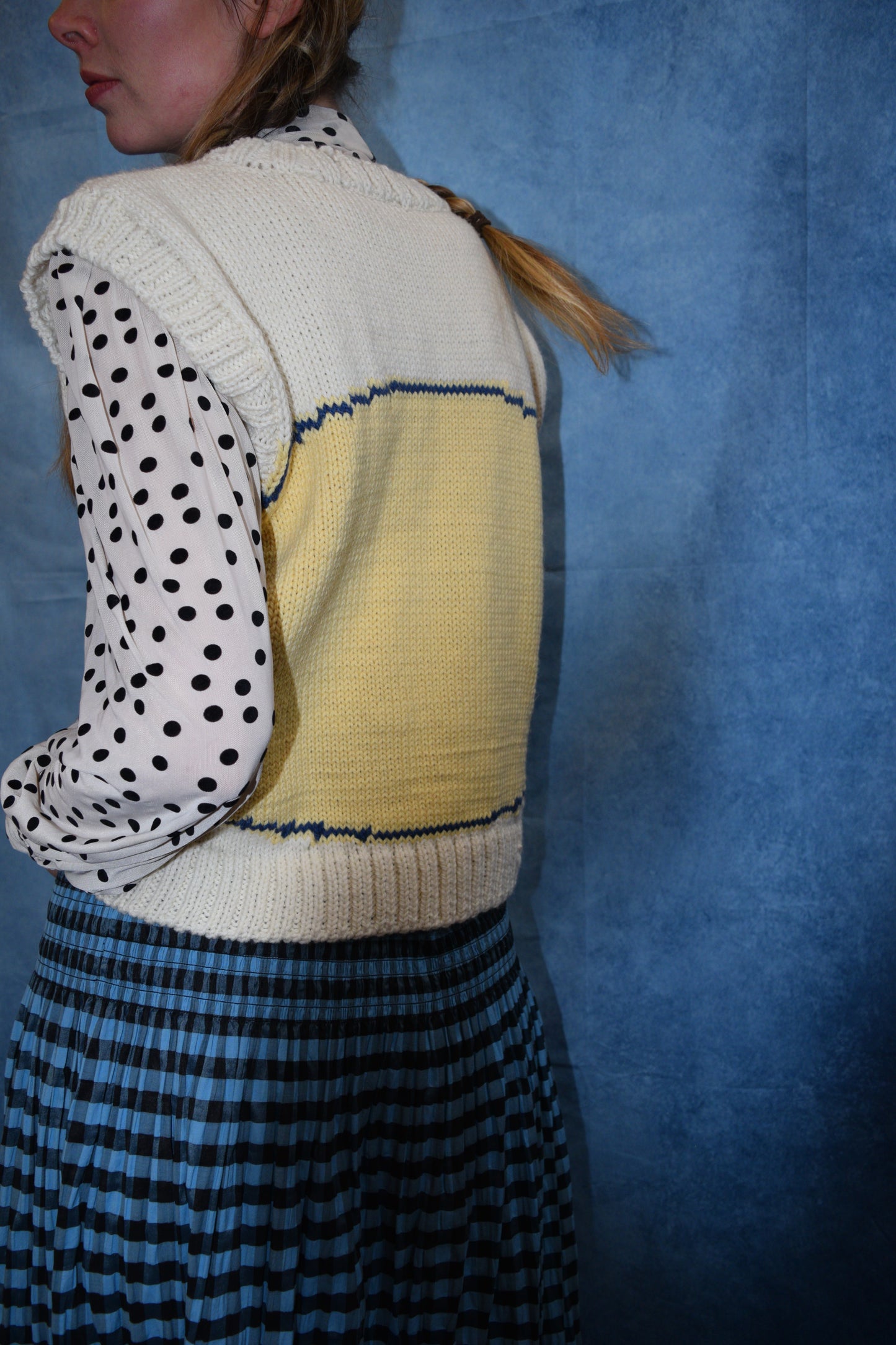 Person wearing a colorful sweater with a patterned design on a blue background