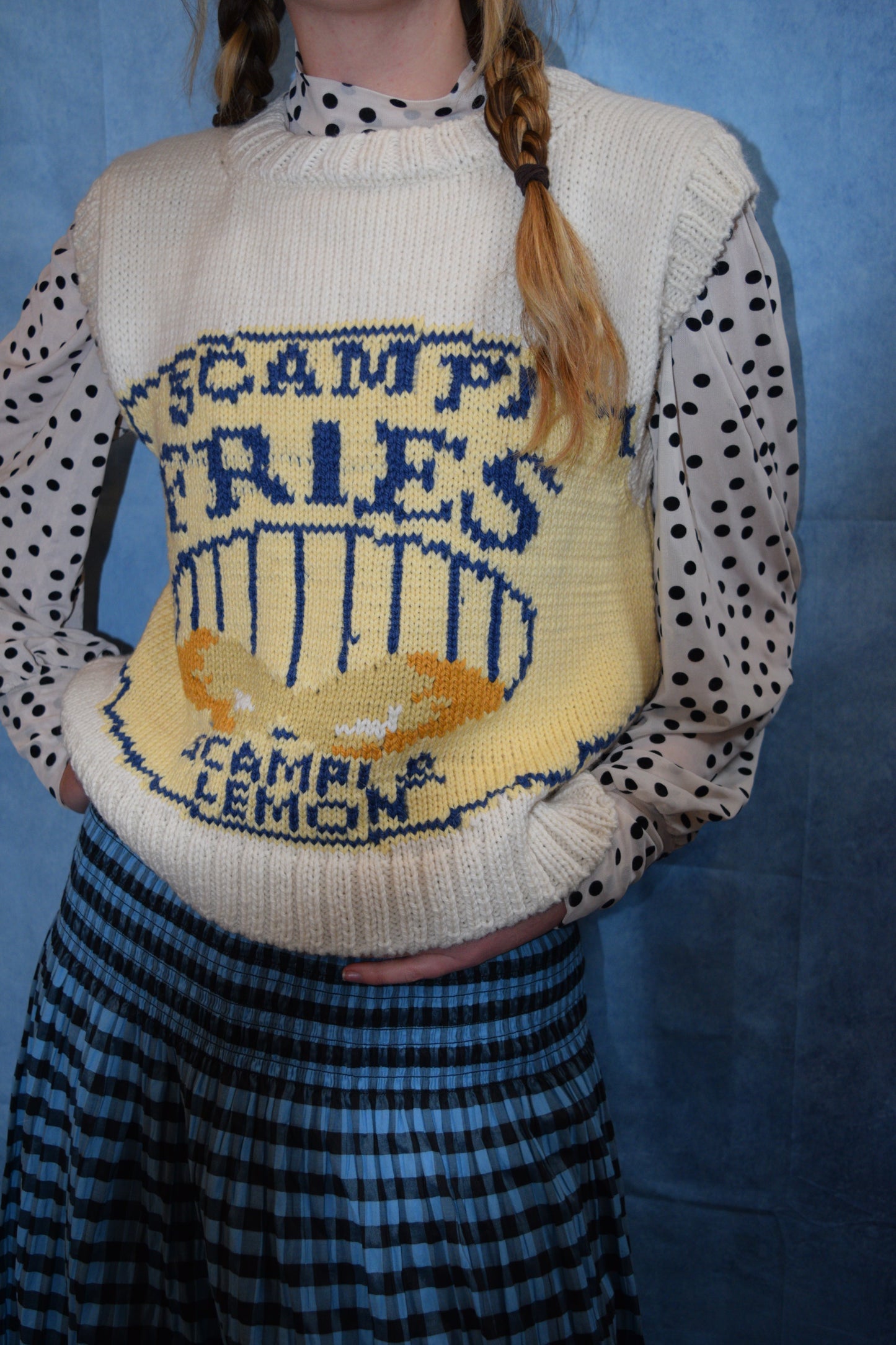 Close-up of a person wearing a knitted sweater with text and graphics on a blue background