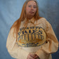 Person wearing a beige sweater with text and a yellow bag on a blue background